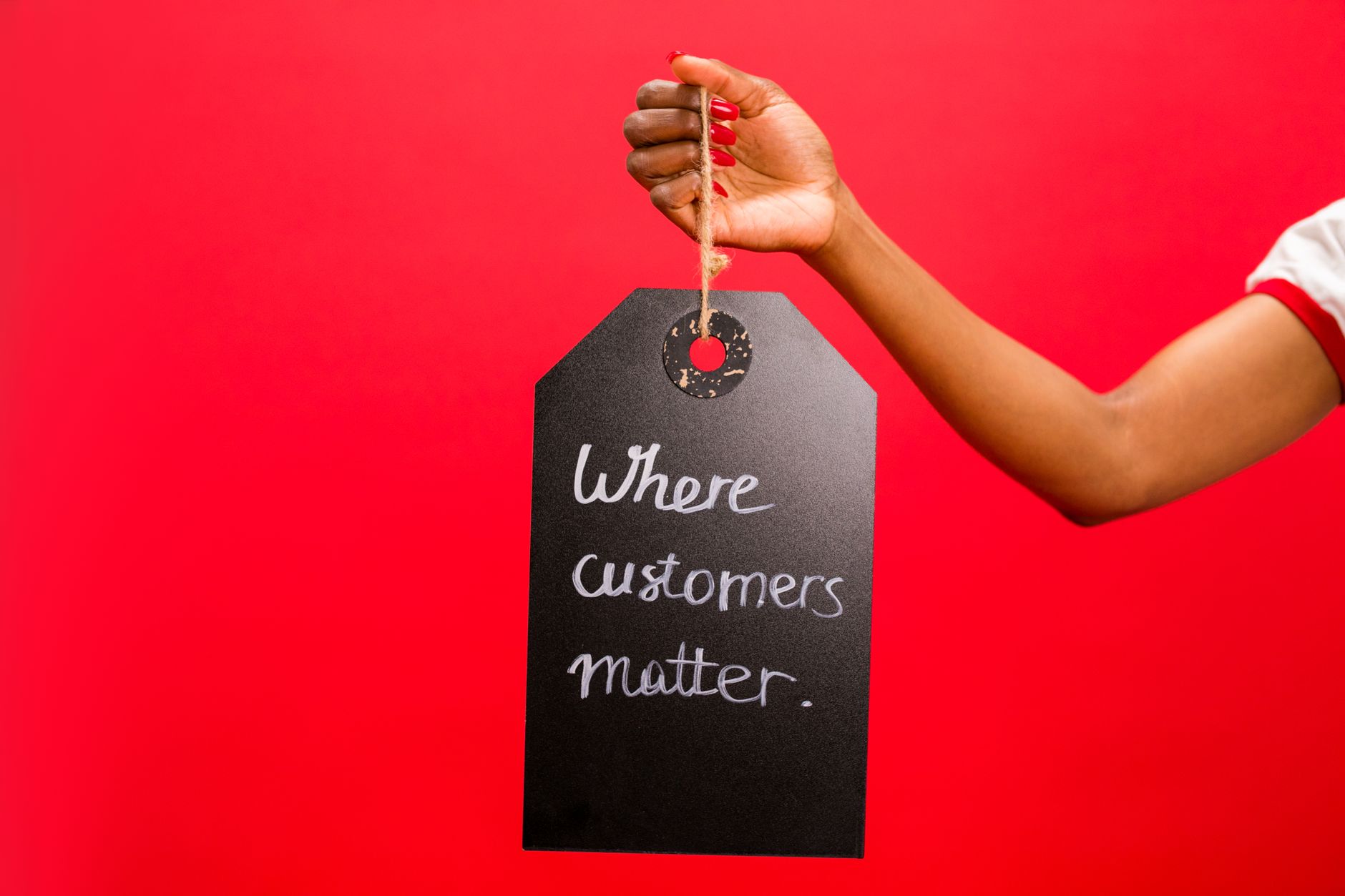 A hand holding a tag with 'Where customers matter' text on a vivid red background, emphasizing customer service.